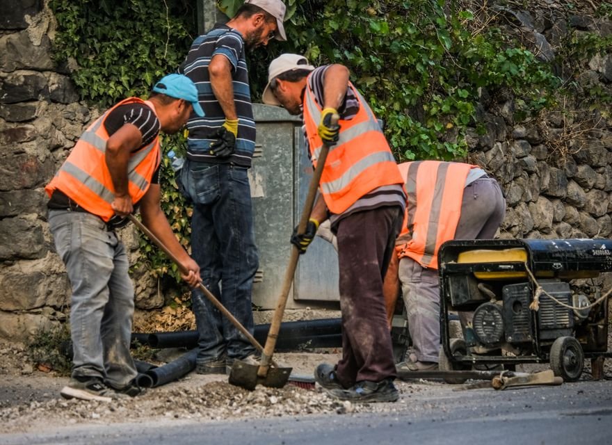 Road construction worker cutting asphalt with safety cones nearby