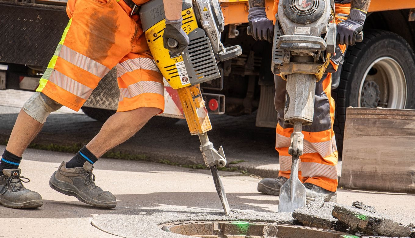 Construction workers breaking asphalt with jackhammers during road work