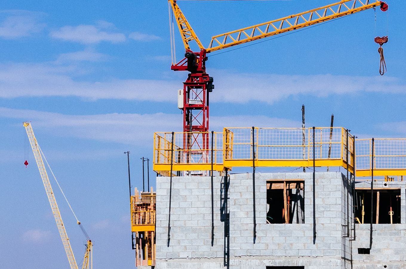 Tower cranes working on a high-rise building under a clear sky