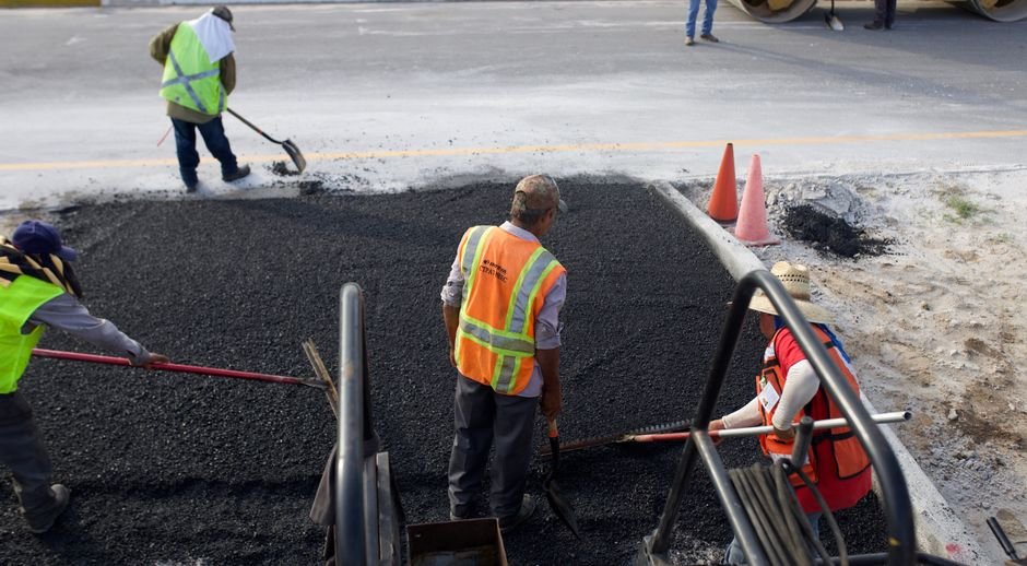 Road construction crew laying fresh asphalt during the day